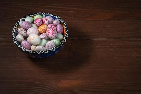 A blue cup with a pattern is filled with multi-colored sugar dragees. Stock Photos
