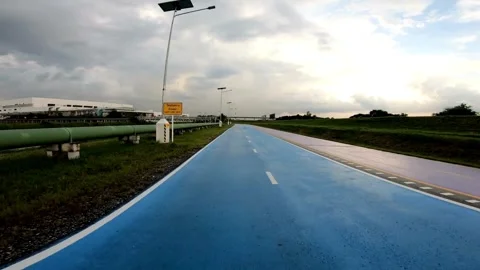 Blue cycling path with warning sign under cloudy sky Video stock 333113973