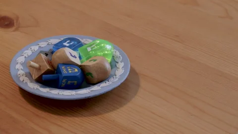Blue decorative bowl of dreidels on table Stock Footage 295923197