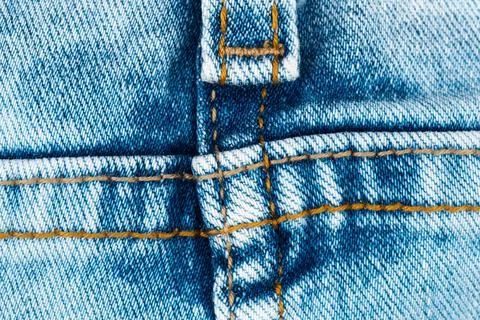 Blue denim fabric texture with orange stitching macro detail on jeans seam Stock Photos