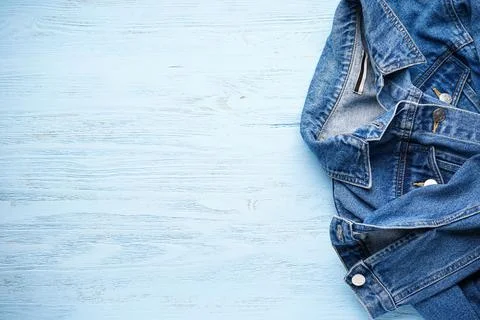 Blue denim jacket on light blue wooden background, space for text. Flat lay. Stock Photos