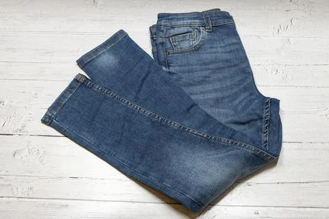 Blue denim jeans rest on a whitewashed wooden surface Stock Photos
