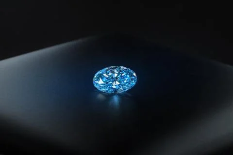 A blue diamond is sitting on a black surface Stock Photos