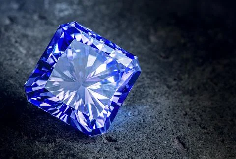 A blue diamond is sitting on a grey surface Stock Photos