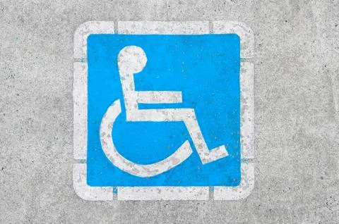 Blue disabled parking sign painted on dark asphalt Stock Photos