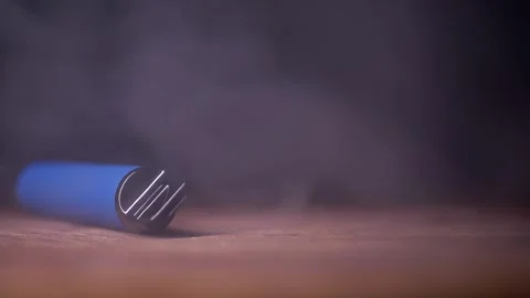Blue Disposable Vape Pen Lying On Wooden Table Surrounded By Thick Smoke Video stock 330114592