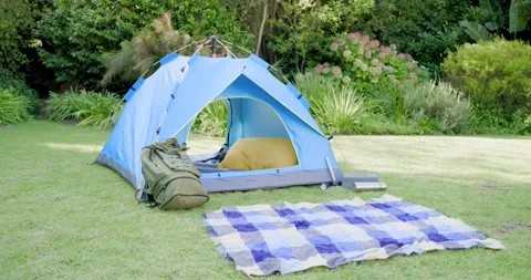 Blue dome tent sitting on grassy lawn, showing yellow bedding, backpack leaning, Stock Footage 342392914