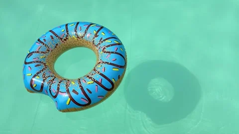 Blue donut pool floats drifting across turquoise swimming pool water on a s.. Stock Footage 334318576