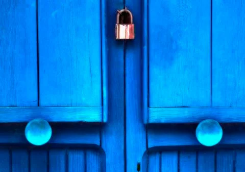 Blue doors with round knobs and a padlock to lock them closed together Foto stock