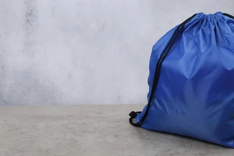 Blue drawstring bag on grey textured table. Space for text Stock Photos