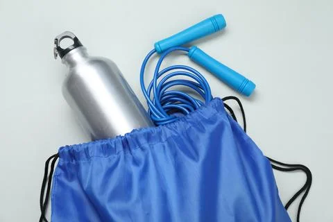 Blue drawstring bag, thermo bottle and skipping rope on grey background, to.. Stock Photos