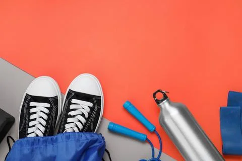 Blue drawstring bag, thermo bottle, skipping rope and sneakers on red backg.. Foto stock