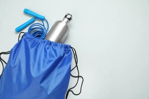 Blue drawstring bag, thermo bottle and skipping rope on grey background, to.. Foto stock