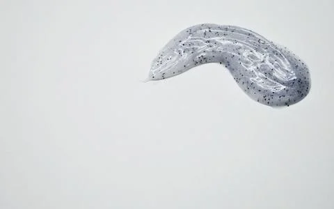 Blue drop of toothpaste with dark specks on white background Stock Photos