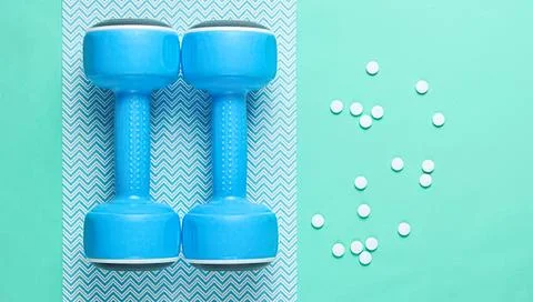 Blue dumbbells on patterned and plain background with pills Stock Photos