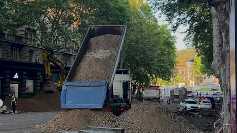 Blue dump truck dumps construction materials on construction site Stockbeeldmateriaal 341275226