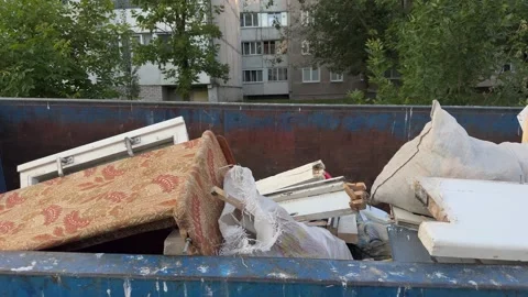 Blue dumpster filled with old mattress, wooden frames and white sacks Vídeos de archivo 340260917