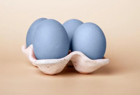 Blue dyed Easter eggs in carton box on beige background. Minimal religious Stock Photos