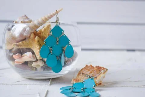 Blue earrings on a white background with seashells in a marine theme Stock Photos