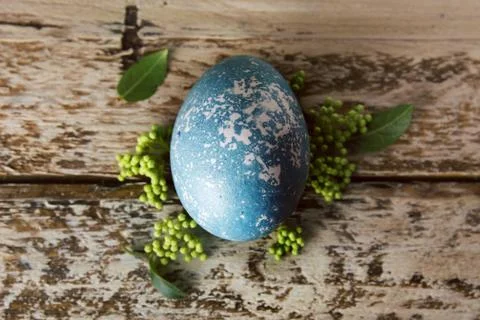 Blue Easter egg, decorated with flowers, on wooden board. Stock Photos