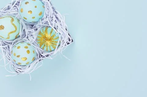 Blue easter egg with gold glitter design in box closeup on blue background, t Stock Photos