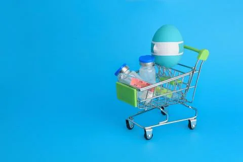 Blue Easter egg in protective medicine mask on shopping cart. Stock Photos