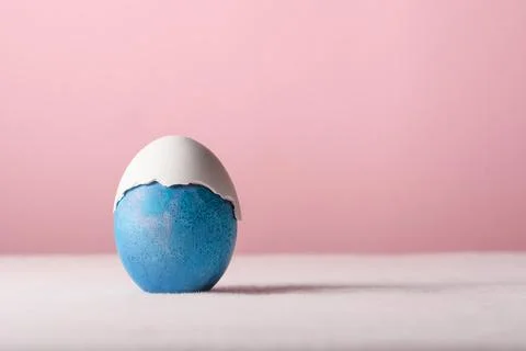 Blue Easter egg wears cracked white shell cap, minimalist pastel still life.. Stock Photos