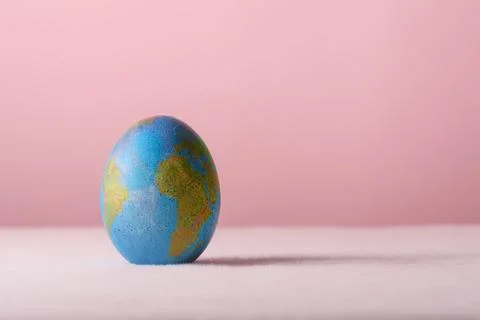 Blue Easter egg with world map stands on pink background as symbol of global Stock-Fotos