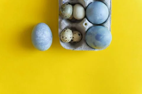 Blue Easter egg on yellow pastel background. Happy Easter concept Organic Stock Photos