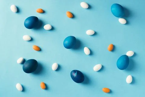 Blue easter eggs and colorful candies on blue background Stock Photos