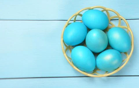 Blue Easter eggs in a basket on a blue background. Stock Photos