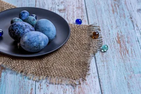 Blue Easter eggs on a dark ceramic plate on burlap on an light wooden backgro Stock Photos