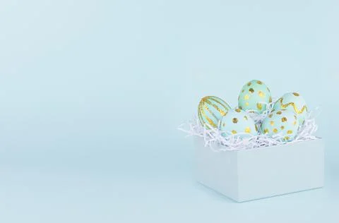 Blue easter eggs with gold glitter design in gift box on blue background, cop Stock Photos