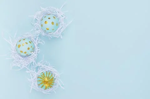 Blue easter eggs with gold glitter dots in white nest as border on blue backg Stock Photos