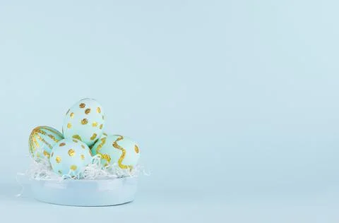 Blue easter eggs with gold glitter design on bowl on blue background, copy sp Stock Photos