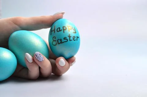 Blue Easter eggs in hands on a gray background. Stock Photos