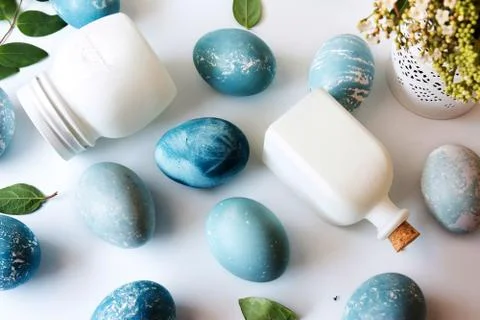 Blue Easter eggs, white bottles and flowers Stock Photos