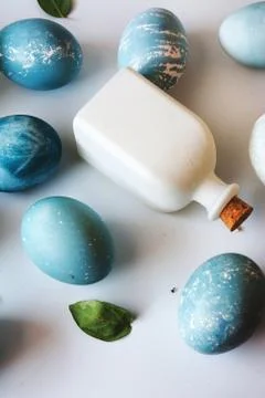 Blue Easter eggs, white bottles and flowers Stock Photos