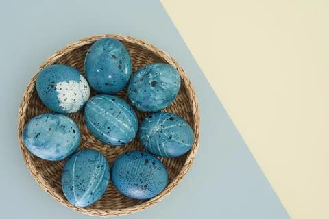 Blue easter eggs in a wicker basket on a two-color yellow-blue background with Stock Photos