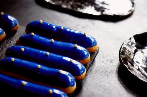 Blue eclairs with a mirrored glaze.A work of culinary art. Cakes Stock Photos