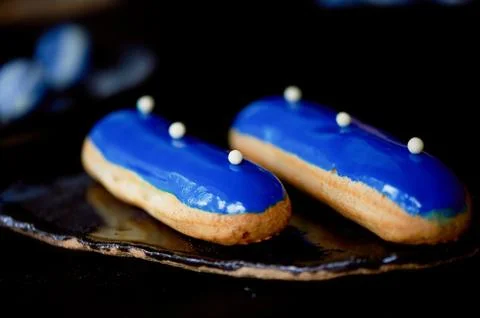 Blue eclairs with a mirrored glaze.A work of culinary art. Cakes Stock Photos