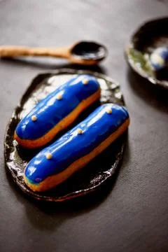 Blue eclairs with a mirrored glaze.A work of culinary art. Cakes Stock Photos