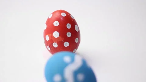 Blue egg with dotted and zigzag pattern hits red chicken egg with polka dots Stock Footage 299933144