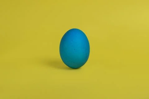 Blue egg on yellow background Fotos de archivo