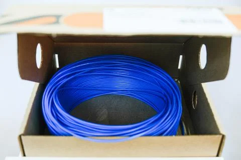 Blue electrical cable coil inside a cardboard box. Professional power wiring Stockfoto's