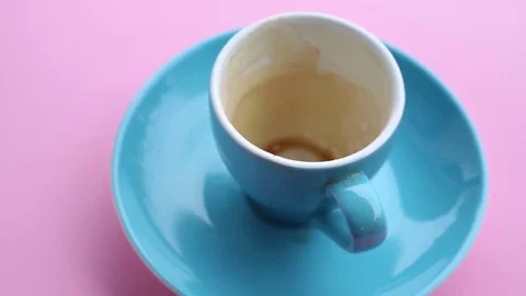 Blue empty cup with rest of coffee on pink rotating plate Stock Footage
