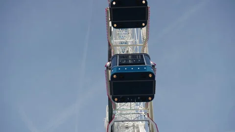 Blue enclosed passenger cabins on a large white observation wheel Stock Footage 340333389
