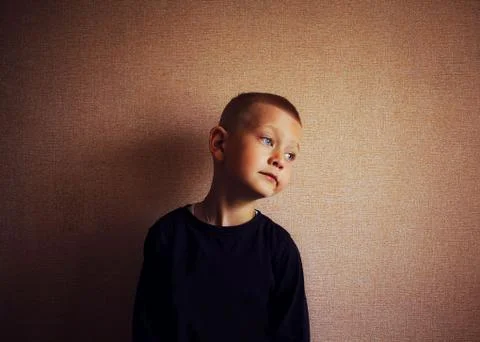 Blue-eyed boy brooding stands against the wall Stock Photos