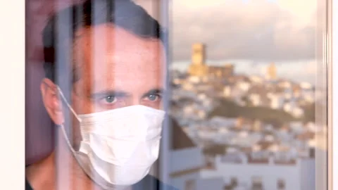 Blue-eyed man with protective mask looking through the window Stock Footage