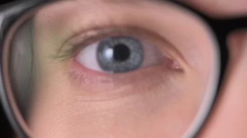 Blue eyes of the girl in glasses close-up, glasses for vision correction Stock Footage